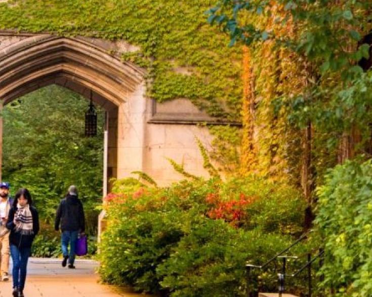 Students walking under arch and garden