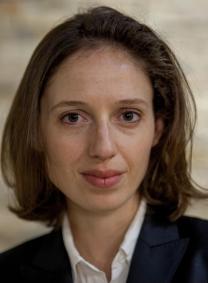 Headshot of a woman with shoulder-length hair in a black suit jacket and white shirt